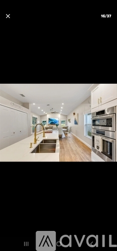 A modern kitchen with white cabinets and a wooden floor.