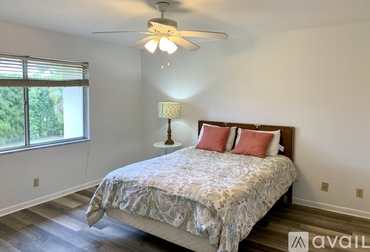 A bedroom with a bed, a ceiling fan, and a window with blinds.
