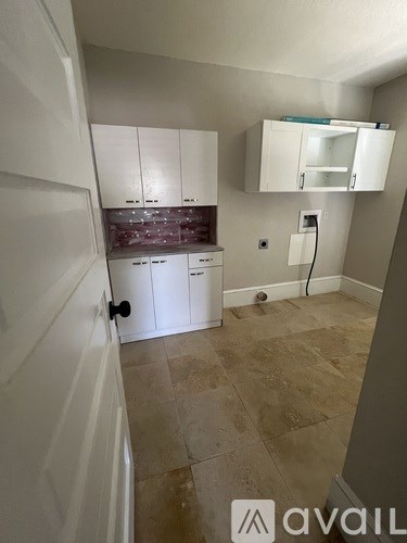 A kitchen area with white cabinets and a tiled floor.
