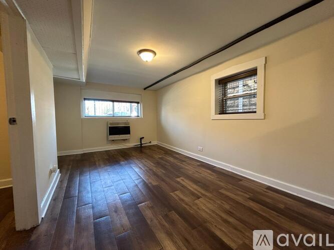 A room with wooden floors and a window with blinds.