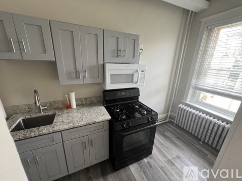 A kitchen with a black stove and a white microwave above it.
