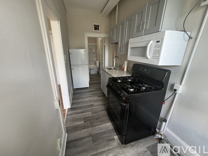 A kitchen with a black stove and white appliances.