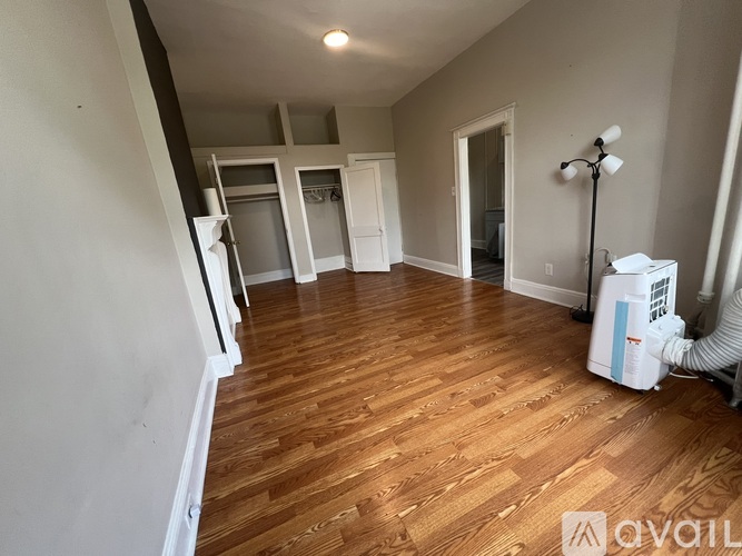 A room with wooden floors and a white wall with a window.