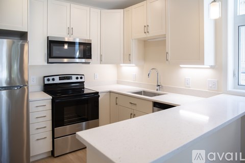 A kitchen with white cabinets and a stainless steel refrigerator.