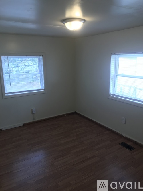A room with wooden floors and two windows.