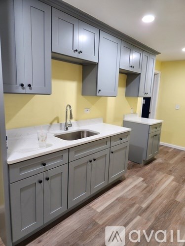 A kitchen with grey cabinets and a sink.