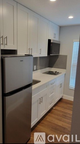 A kitchen with white cabinets and a black microwave.