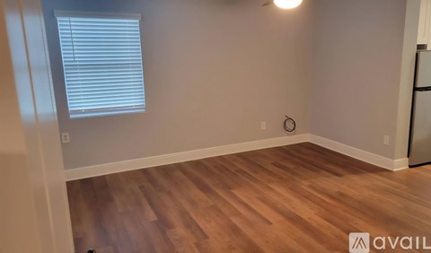 A room with wooden flooring and a window with blinds.