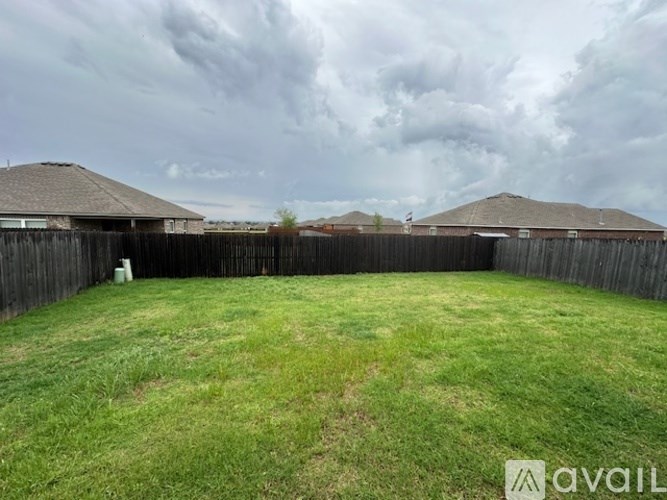 A backyard with a wooden fence and a grassy area.
