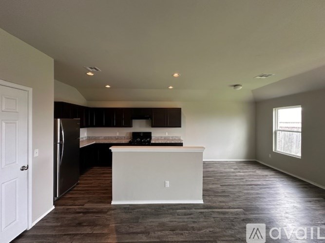 A kitchen with a black refrigerator and a white island.