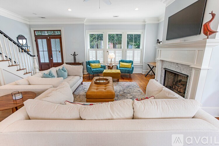 A living room with a white couch, a fireplace, and a television on the wall.