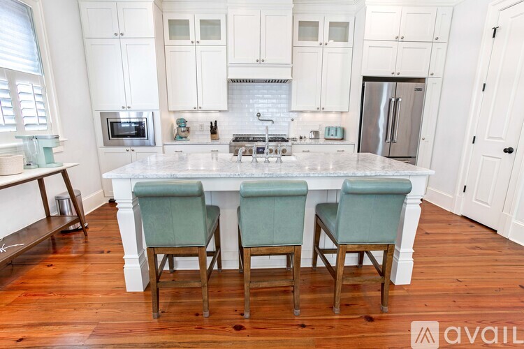 A kitchen with white cabinets and a central island with two chairs.