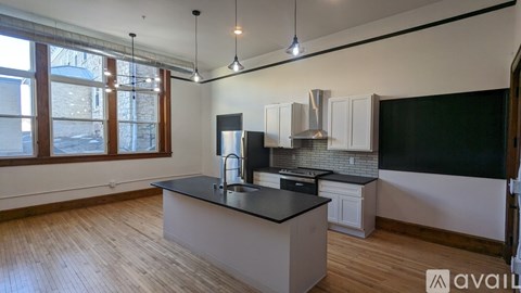 A kitchen with a black countertop and wooden flooring.