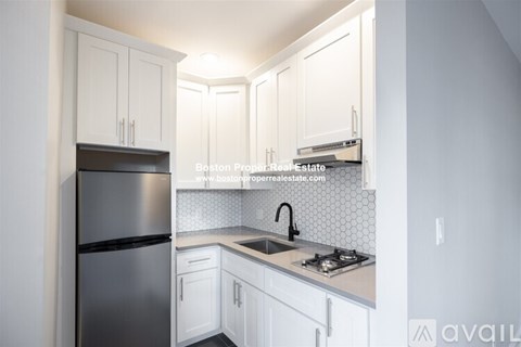 A kitchen with white cabinets and a stainless steel refrigerator.