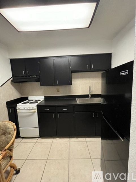 A kitchen with black cabinets and a white dishwasher.