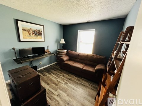 A living room with a brown couch, a flat screen TV, a wooden staircase, and a painting on the wall.