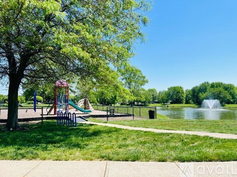 A playground with a slide and a pond in the background.
