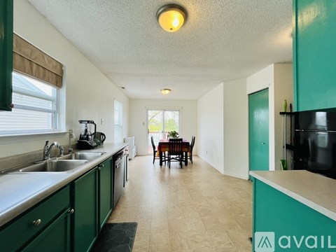 A kitchen with green cabinets and a dining area with a table and chairs.