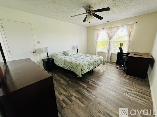 A bedroom with a bed, dresser, and window.