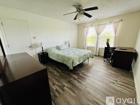 A bedroom with a bed, dresser, and window.