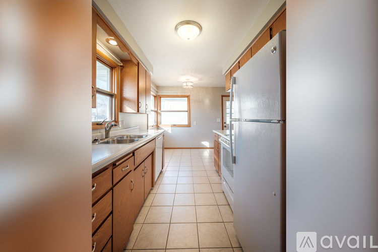 A kitchen with a refrigerator, sink, and cabinets.
