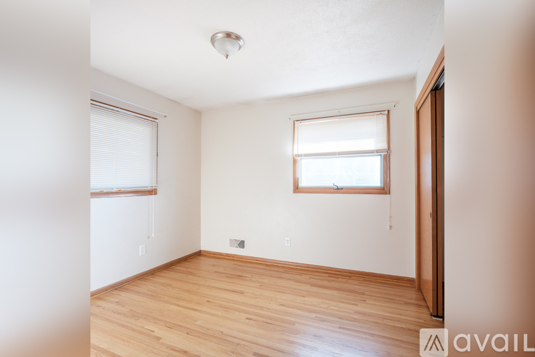A room with wooden floors and a window with blinds.
