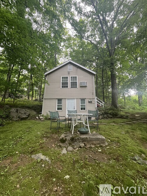 A small house with a porch surrounded by trees.