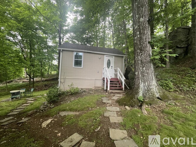 A small house with a porch is surrounded by trees.