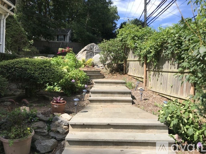 A garden with a stone wall and steps leading up to a house.