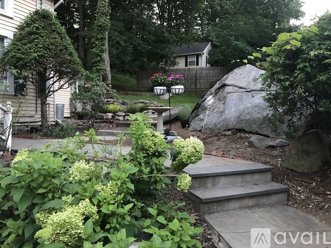 A garden with a large rock and a statue.