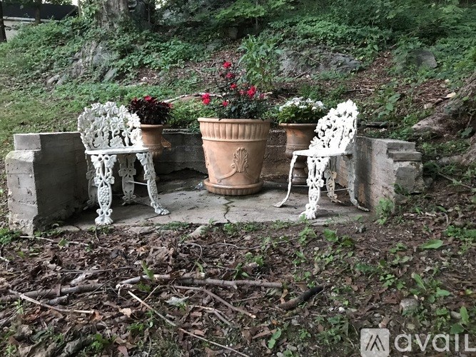 A white chair is placed in front of a brown pot.