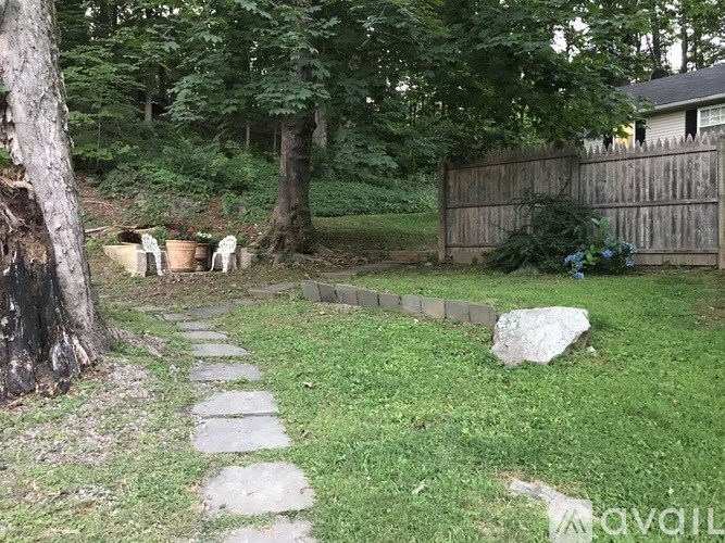 A backyard with a stone pathway and a large rock.