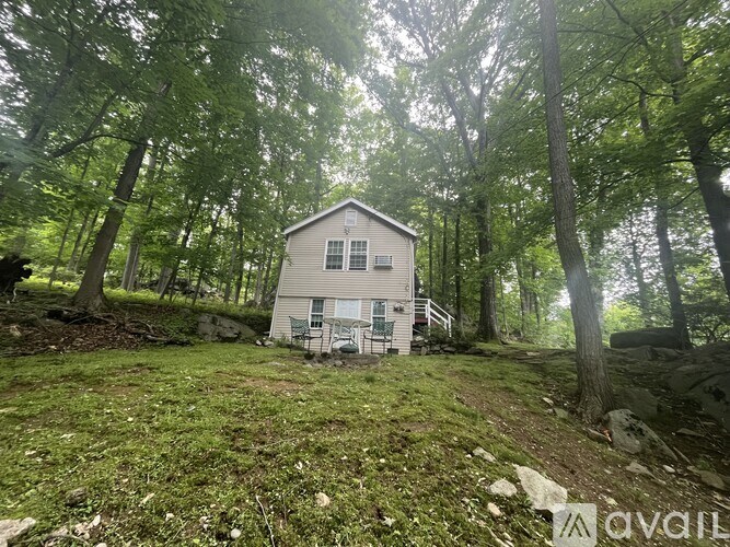 A small house is surrounded by trees in a wooded area.