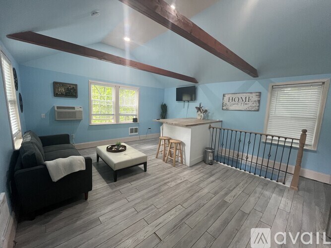 A living room with a black couch and a wooden coffee table.