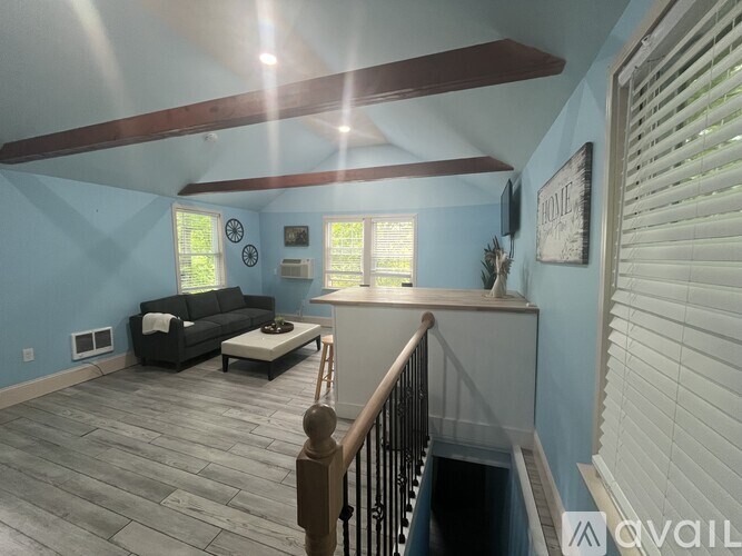 A living room with a couch, a coffee table, and a staircase.