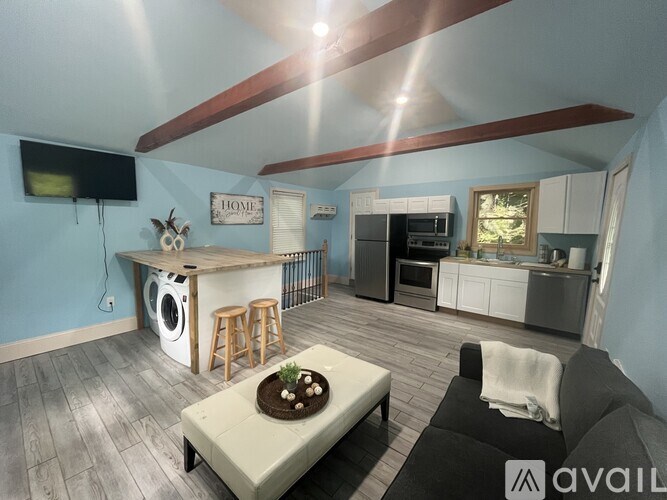 A living room with a washing machine and a flat screen TV mounted on the wall.