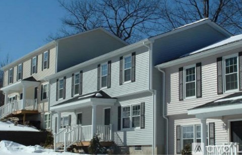 A row of houses with white siding and dark shutters.