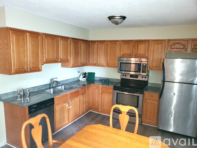A kitchen with wooden cabinets and a stainless steel refrigerator.