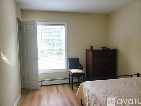 A bedroom with a bed, chair, and window.