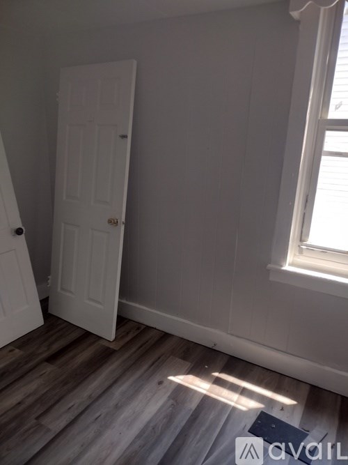 A room with a white door and a window with sunlight coming through.