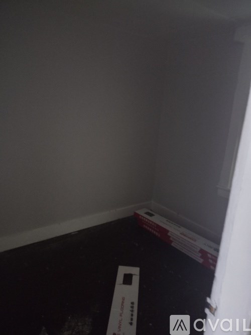 A room with a white wall and a black floor with a white box on it.