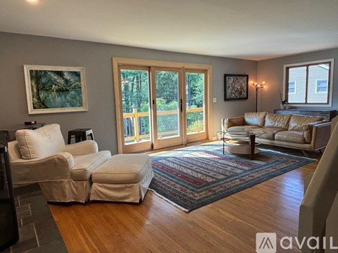 A living room with a couch, chair, rug, and a painting on the wall.