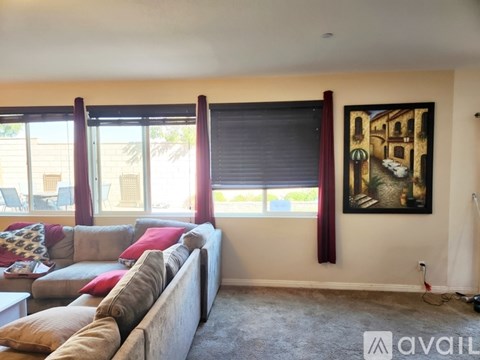 A living room with a couch, pillows, and a painting on the wall.