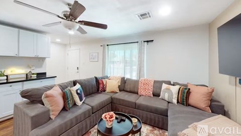 A living room with a grey couch and a ceiling fan.