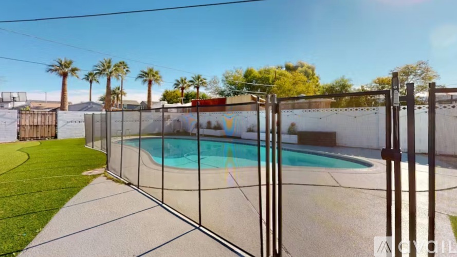 A pool surrounded by a fence with palm trees in the background.