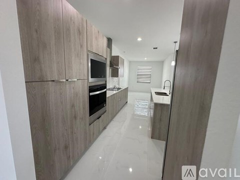 A modern kitchen with wooden cabinets and a white floor.