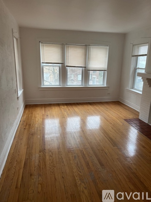 A room with wooden floors and a window with blinds.