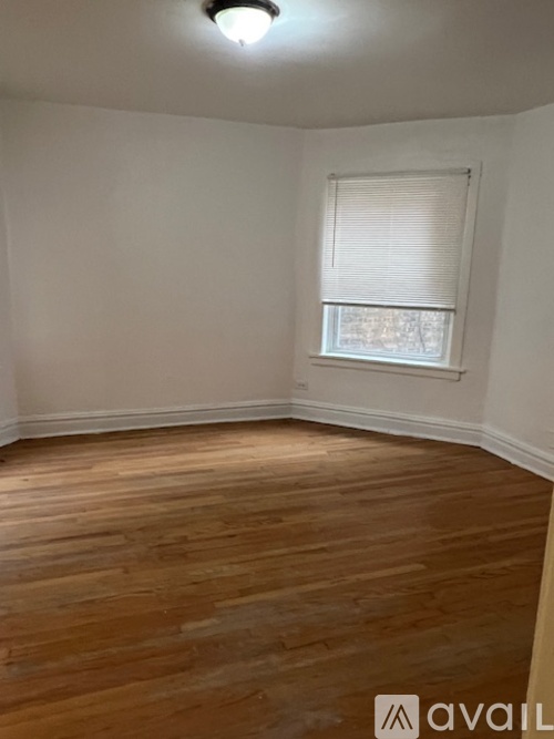 A room with wooden flooring and a window with blinds.
