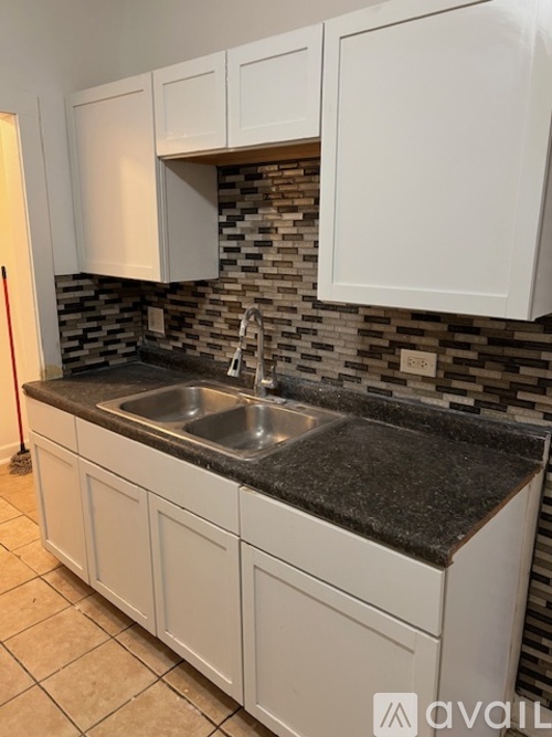 A kitchen with white cabinets and a black countertop.