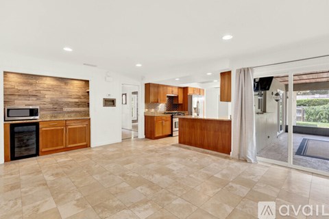 A spacious kitchen with wooden cabinets and a tiled floor.
